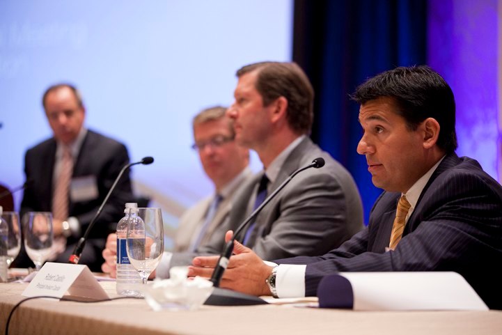 Speakers talking at a panel table at a conference