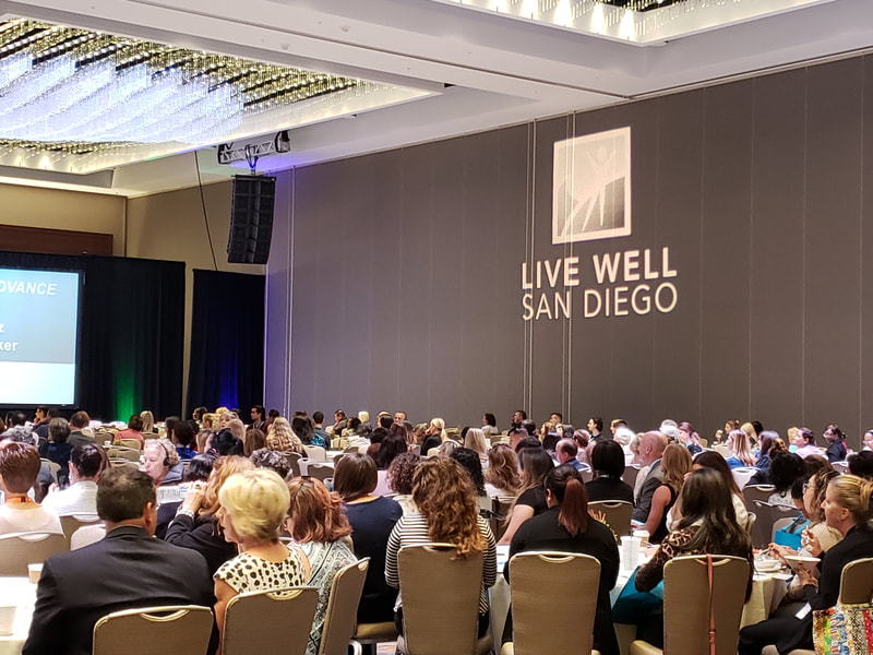 Live Well San Diego logo projected on a wall with conference attendees
